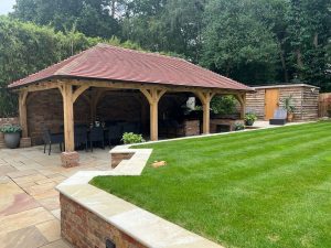 Spacious oak gazebo with a hipped roof in a landscaped backyard