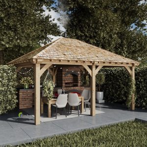 The Grayling gazebo, a 4 x 6m structure with a hipped roof and two bays, showcasing a modern design. Its elegant gray wooden construction is situated in a backyard, offering a shaded area with comfortable seating and a small coffee table beneath.