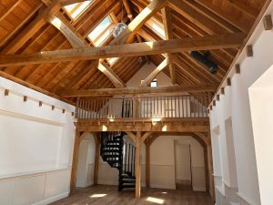 A residential home featuring a green oak queen post truss, providing both structural support and aesthetic appeal to the high ceiling space