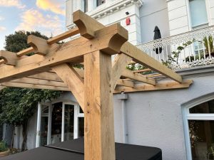 Oak lean-to pergola attached to a house, offering a stylish outdoor extension