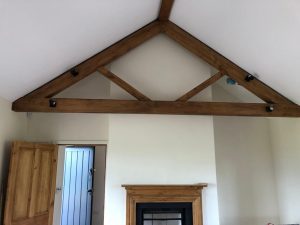 Open living space with exposed oak queen post trusses, providing structural support and an aesthetic appeal