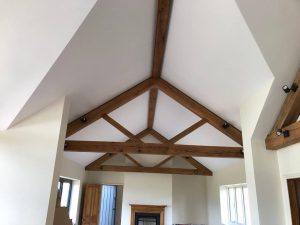 Close-up of oak queen post trusses showcasing the connection between the vertical posts and horizontal chords