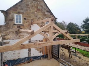 Installation of a raised tie king post truss, highlighting its robust oak framework
