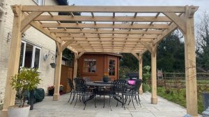 Bespoke oak pergola with lattice panels for climbing plants, elegantly positioned near a house.