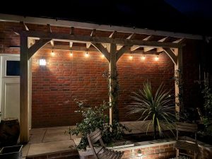 Small oak lean-to pergola attached to a house, featuring compact solid oak frame ideal for patios or entrances