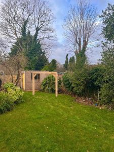 Sturdy oak swing frame in a garden setting, perfect for outdoor relaxation.